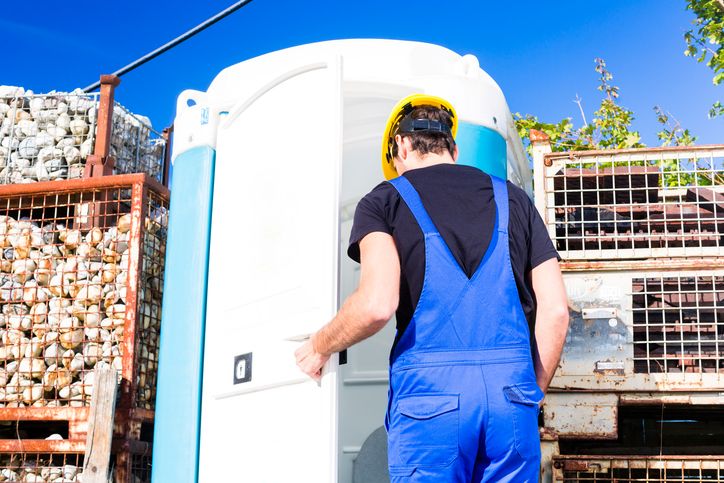 Worker entering portable toilet at outdoor construction site