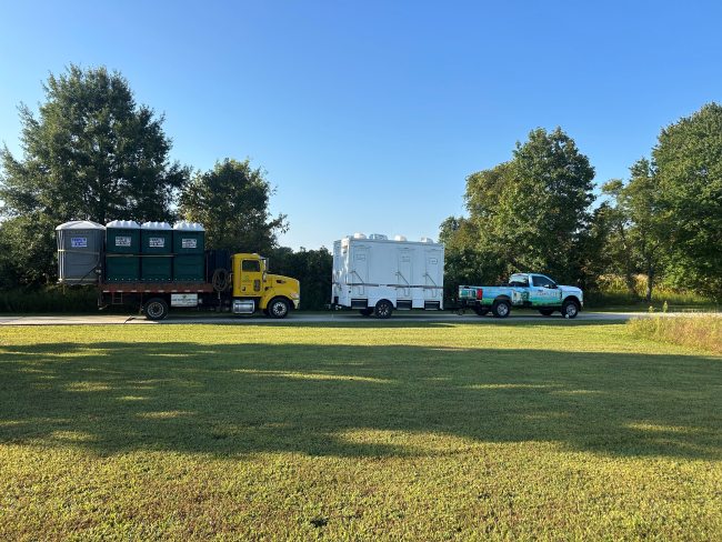 Portable restroom trailer, service truck and toilets parked near event grounds in Paulsboro, NJ